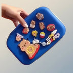 Blue case with colorful animal-shaped stickers held by a hand against a light gray background
