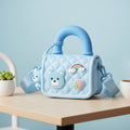 Mango Muffins light blue quilted sling bag with bear, strawberry, and rainbow appliques and a top handle.