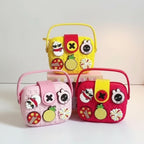 Mango Muffins Signature Series Charmer Sling crossbody bag for kids in pink, yellow, and red. Features EVA material, customizable charms, and a snap flap closure.