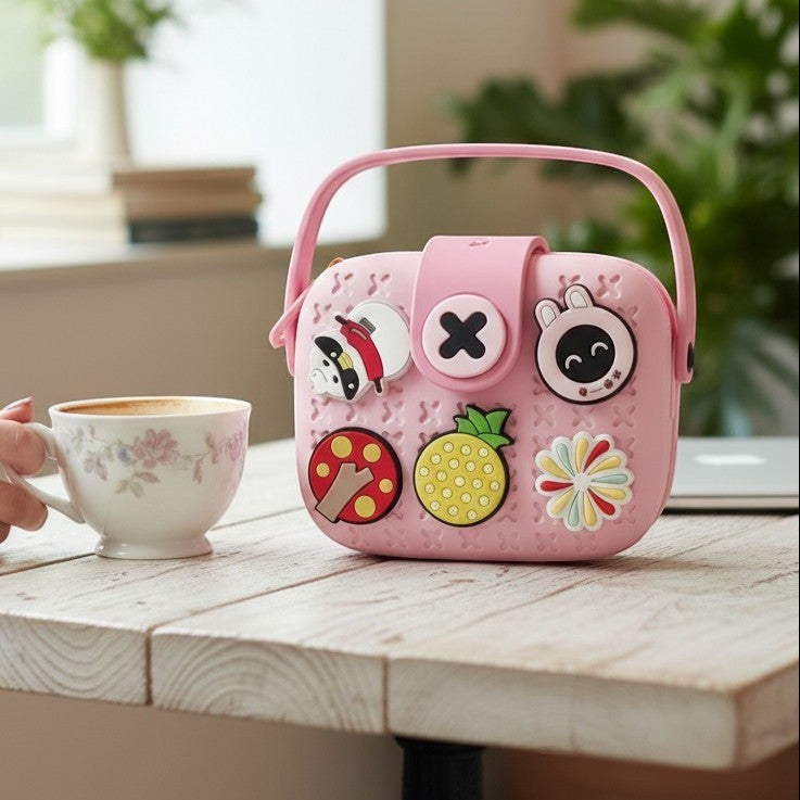 Mango Muffins pink EVA sling bag for kids, customizable with fun 3D charms like a pineapple and mushroom.