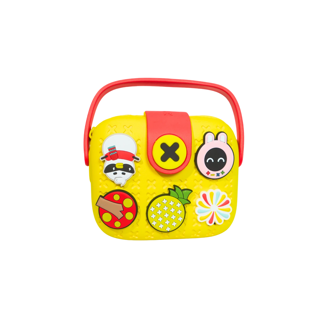 Mango Muffins yellow EVA crossbody sling bag for kids with red handle and customizable charms like a raccoon, pineapple, and bunny.